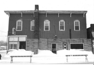 An old building with snow piles in front